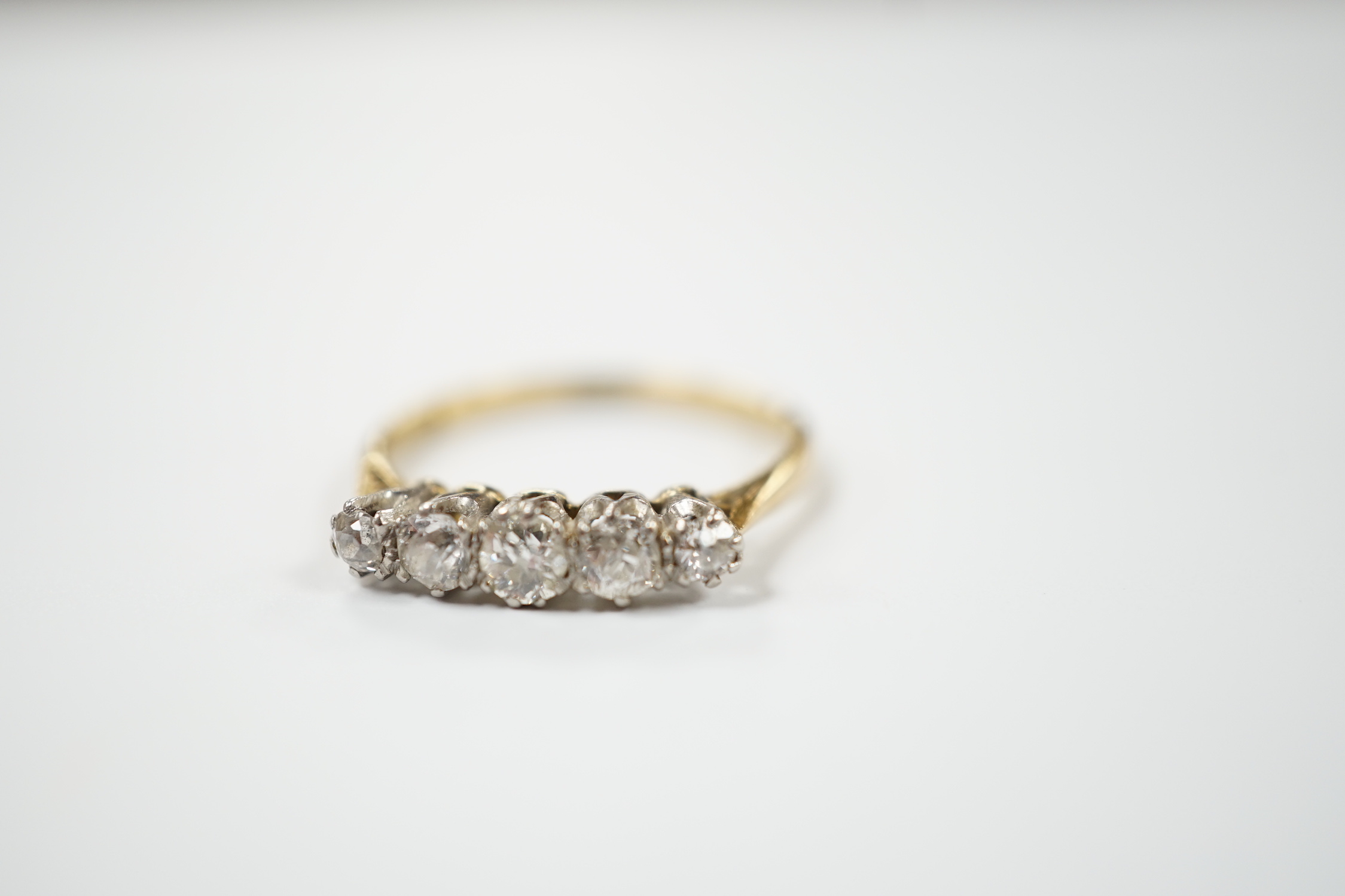 An 18ct and graduated five stone diamond set half hoop ring, size N, gross weight 2.5 grams.